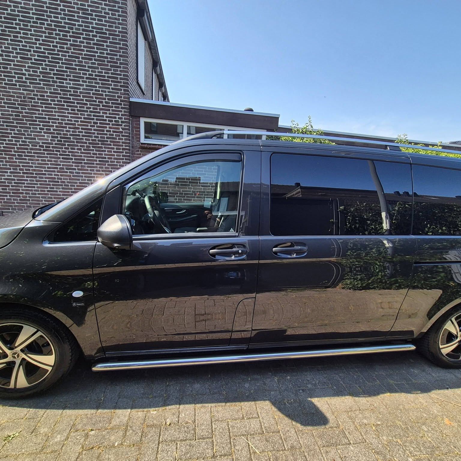 Dezelfde zwarte bus na de behandeling, de lak spiegelt het huis ernaast