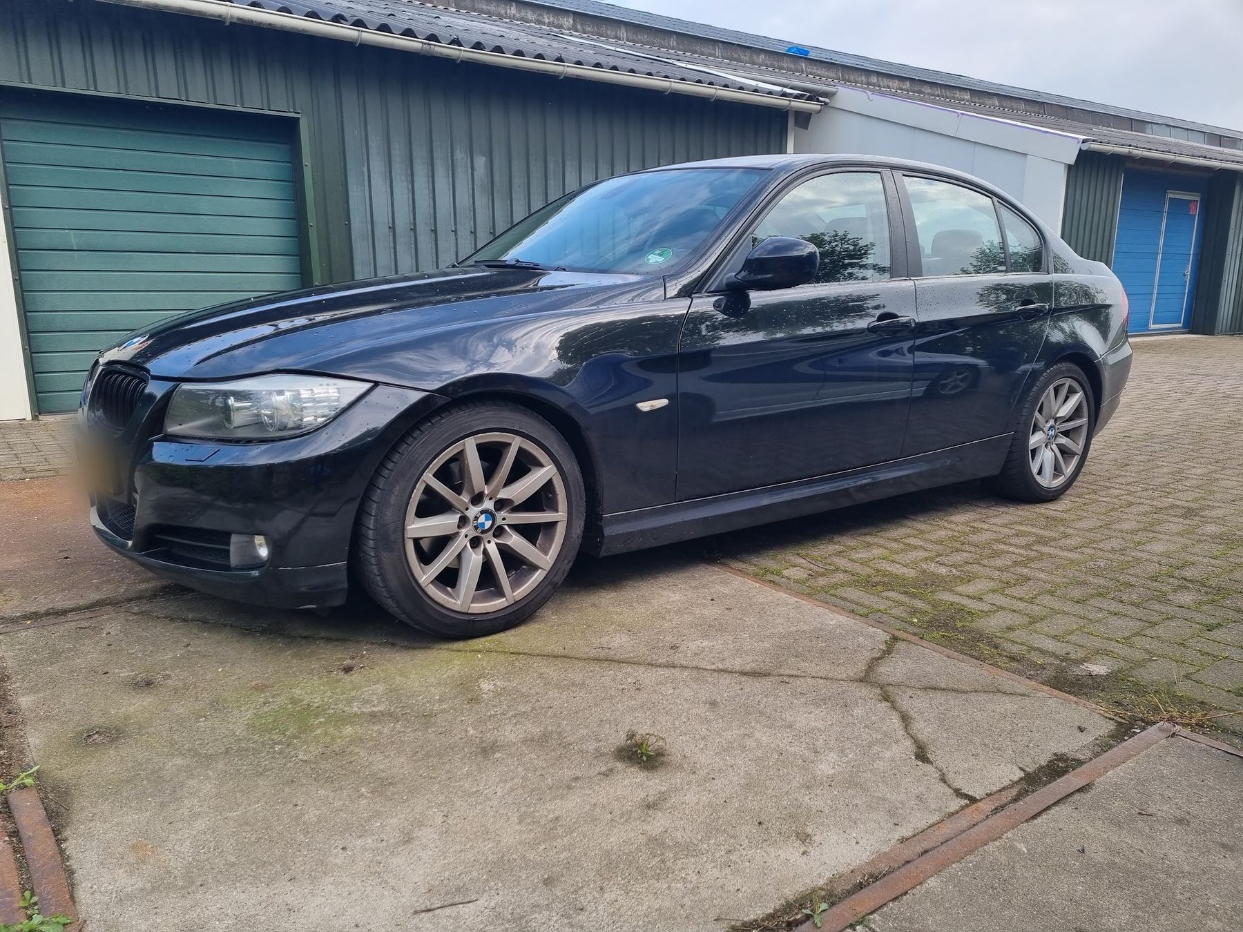 Donkerblauwe BMW 3-serie met glanzende lak voor een rij garagedeuren
