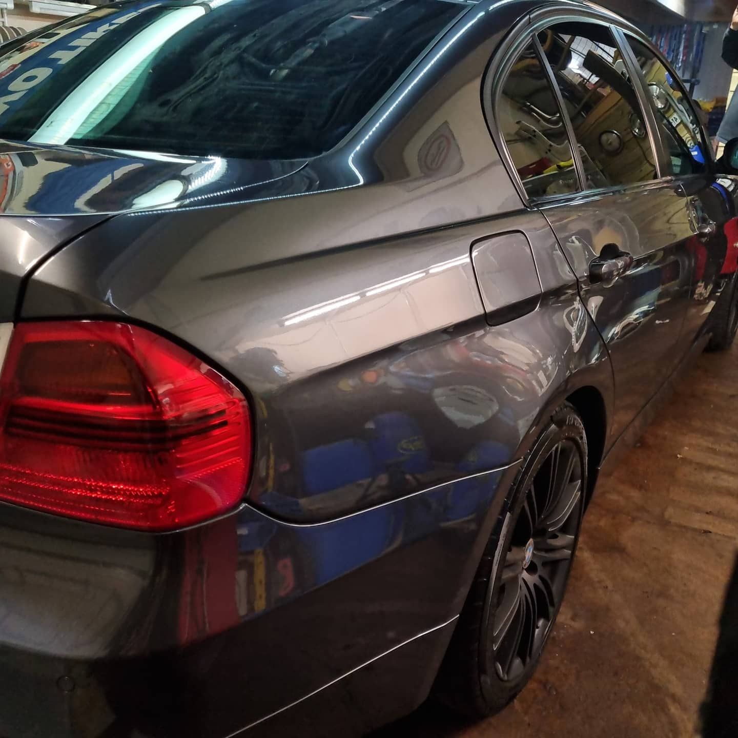 Grijze BMW 3-serie met de werkplaatslampen gespiegeld in de lak
